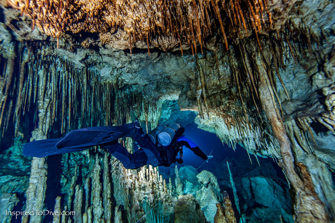 Cave diver passing between formations in a cave in Mexico
