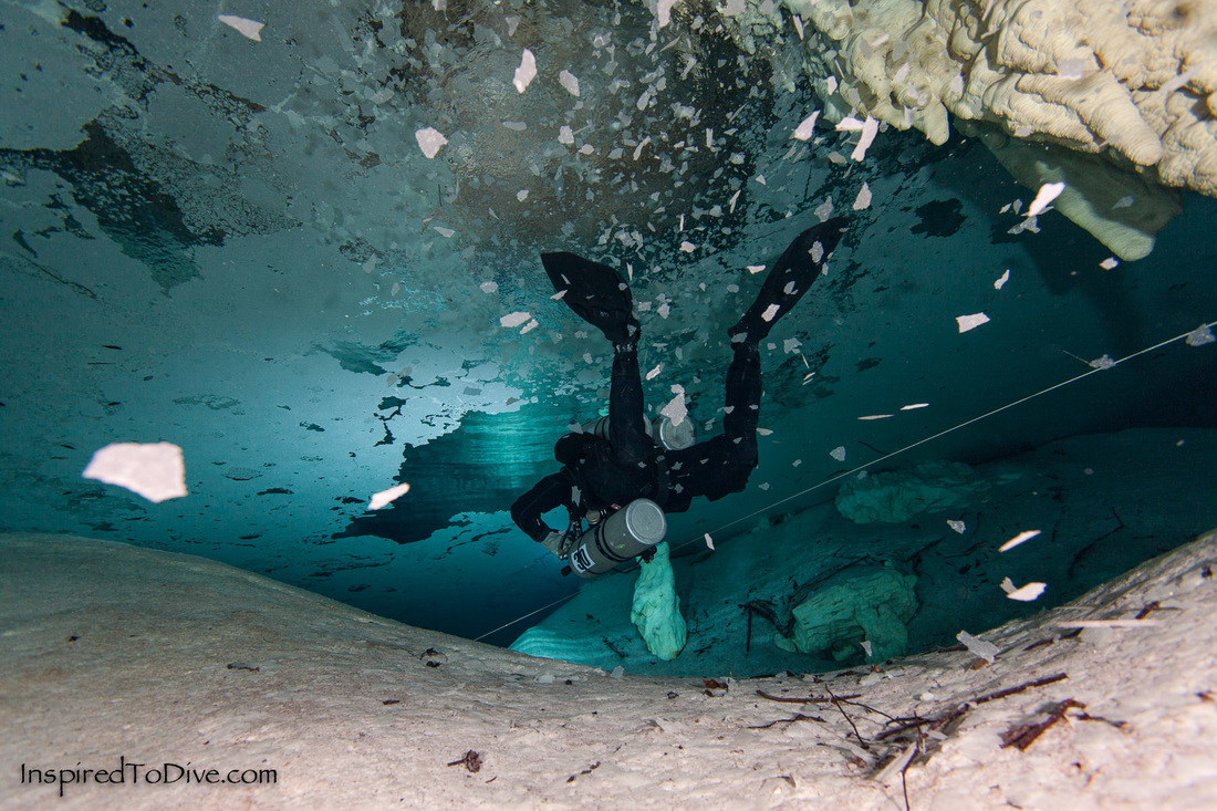 A cave diver exhales and breaks up an overhead calcite raft