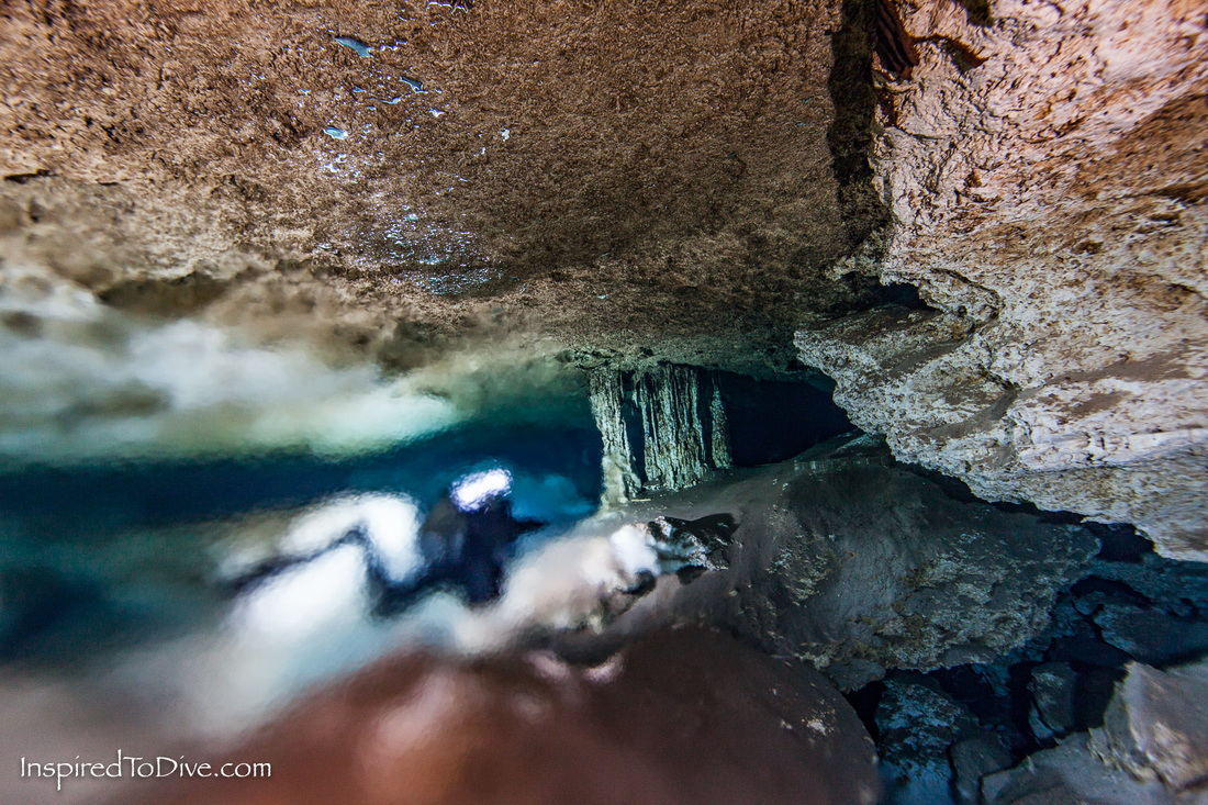 Cave diver swimming through a halocline in a cave in Mexico