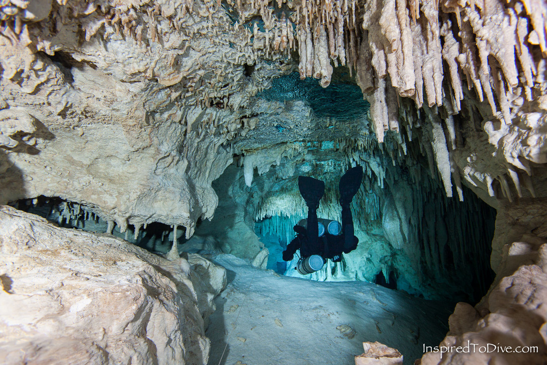 Scuba diver exiting cave system with underwater photographer behind in the Riviera Maya in Mexico